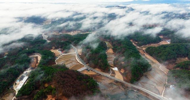 Aerial View of Village and Road Over Foggy Lake