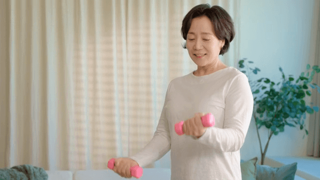 여성이 실내에서 덤벨 운동을 하는 모습