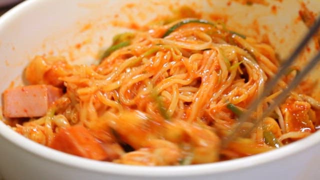 Jjolmyeon with ham and green onion mixed in a bowl