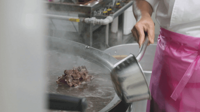 Person straining impurities from a large pot