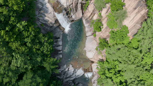 Waterfall dropping into clear pool in forest valley