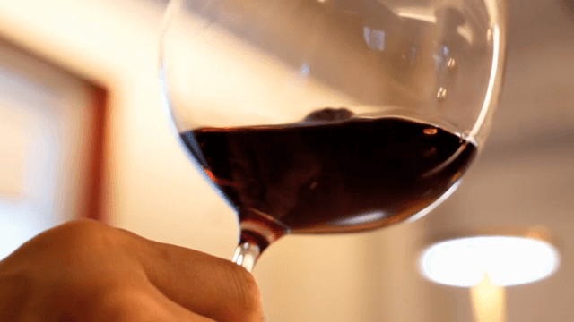 Glass of red wine being swirled indoors