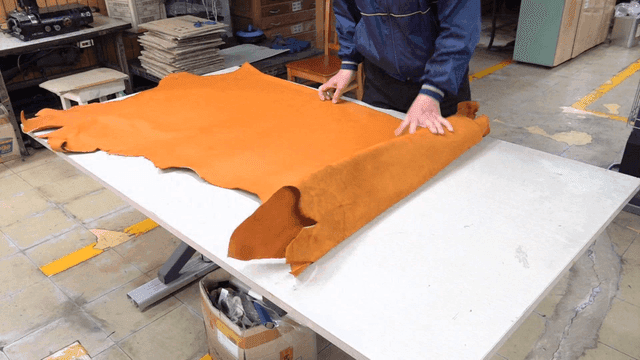 Worker spreading leather on table