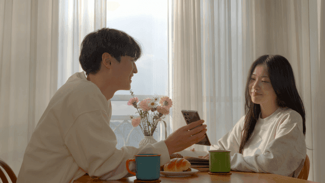 Couple looking at smartphone together by window in morning