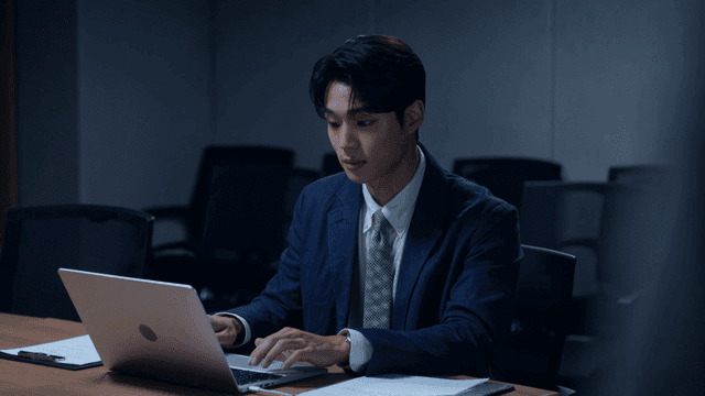 Male office worker working late on his laptop in conference room