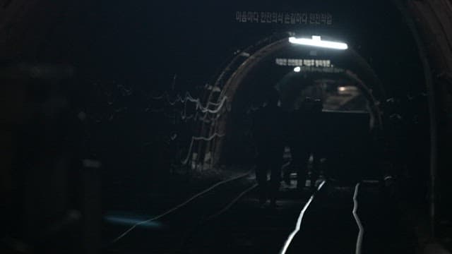 Miners walking on the tracks in a dark coal mine