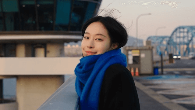 Woman in a blue scarf smiling on a bridge