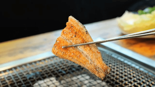 Eel on a grill held with chopsticks