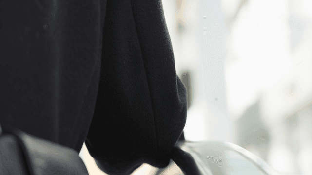 Back view of a woman in a black coat going up an escalator