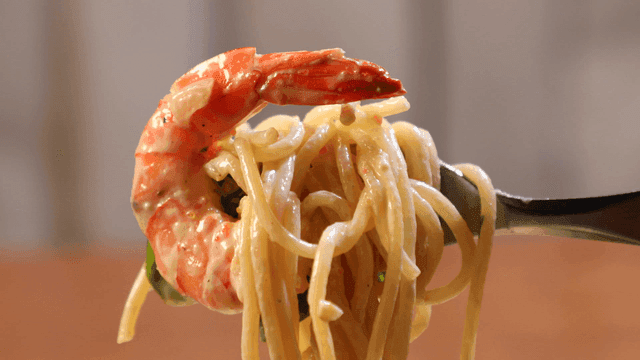 Fork lifting shrimp pasta with cream sauce