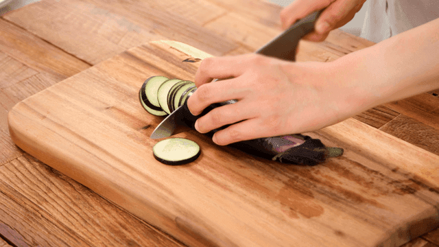 Slicing an eggplant on a wooden board