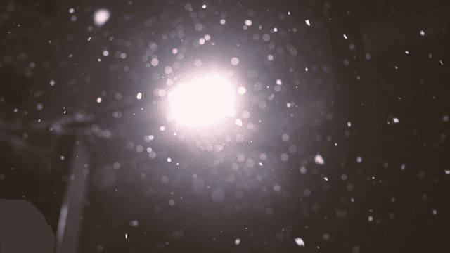 Snowflakes falling under a bright streetlight