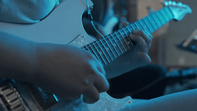 어두운 방에서 기타 연주하는 사람