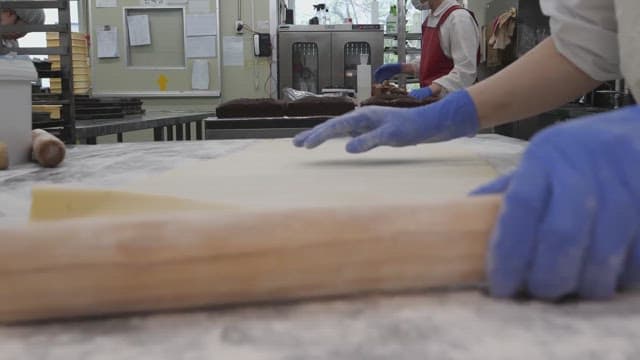 Rolling out dough with a rolling pin in a bakery kitchen