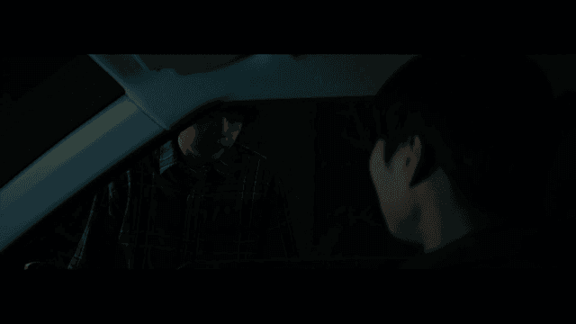 Two people talking through a car window at night