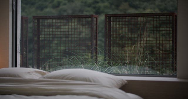 창가에 푸른 초목이 보이는 침실