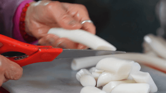 Hands of old man cutting rice cakes with scissors