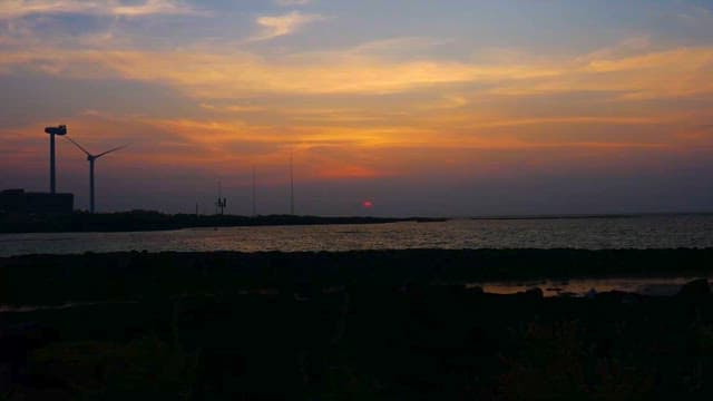 일몰의 해안가와 풍력 발전기