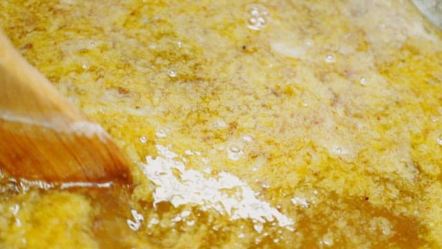 Stirring boiling wax in a pot with a wooden spatula