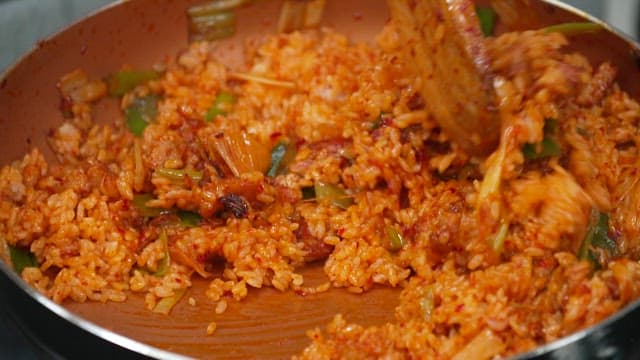 Green onion kimchi fried rice being stirred in a pan