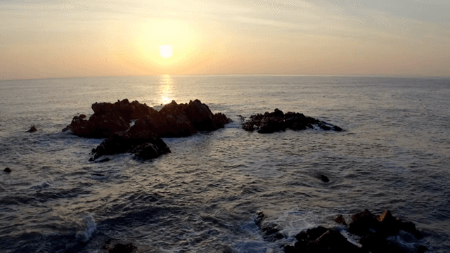 바위 섬이 있는 바다 위의 일몰