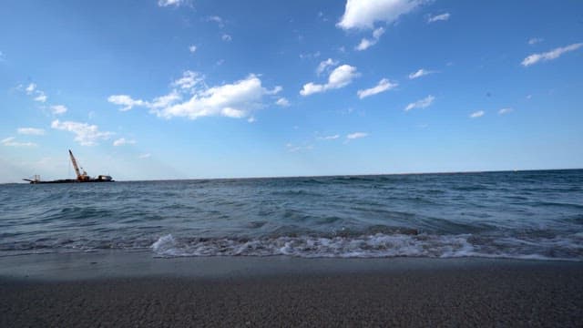 먼 배경에 건설 크레인이 있는 해안가 파도