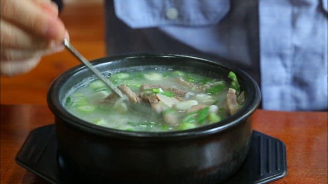 숟가락으로 설렁탕을 젓는 사람