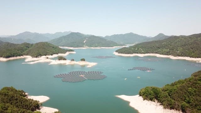 푸른 언덕으로 둘러싸인 호수 위 수상 태양광 패널