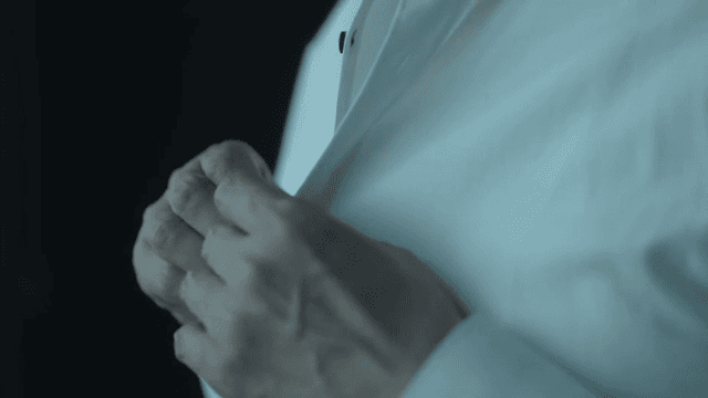 흰 셔츠의 단추를 잠그는 사람