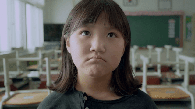 Child lost in thought looking at the bulletin board in the classroom