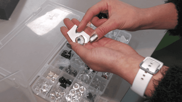 Person examining decorative eyes on a table