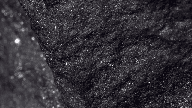 Shiny and dark rock surface illuminated by light