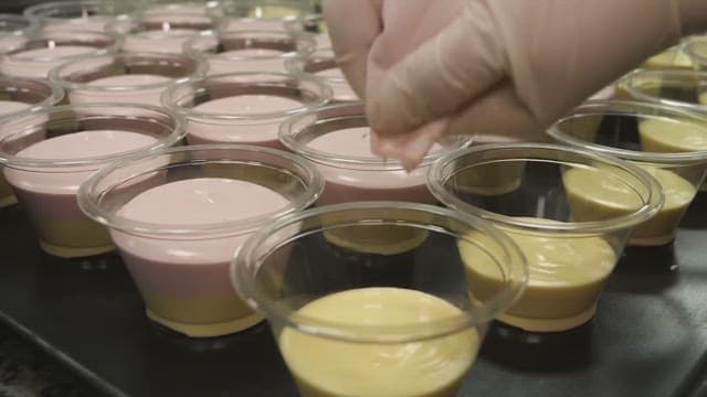 Pouring pink mousse into a plastic container containing yellow mousse