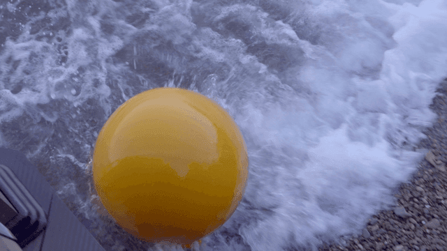 Yellow buoy on a rocky shore with waves