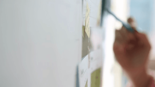 펜으로 보드를 가리키며 회의하는 손