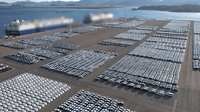 Large cargo ship and parked cars at port