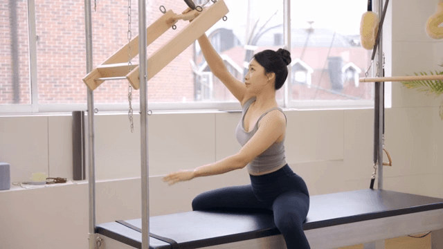 Woman practicing pilates using equipment indoors