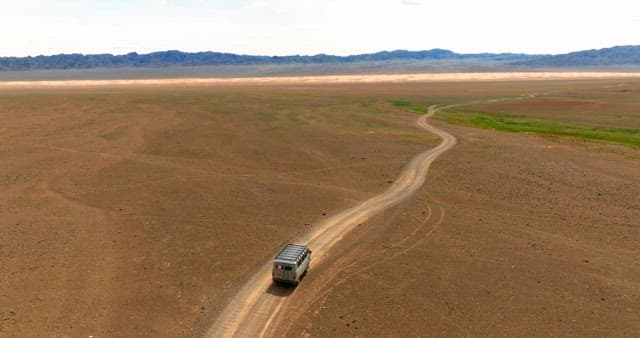 Van traveling through a vast desert landscape