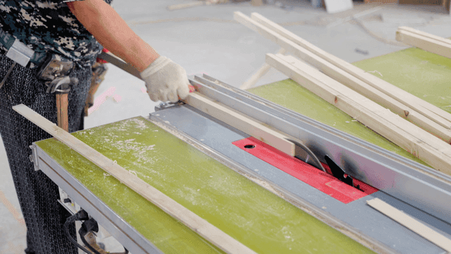 Worker using table saw in workshop