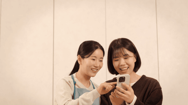 Mother and daughter laughing while looking at their cell phones