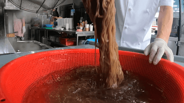주방에서 면을 헹구는 요리사