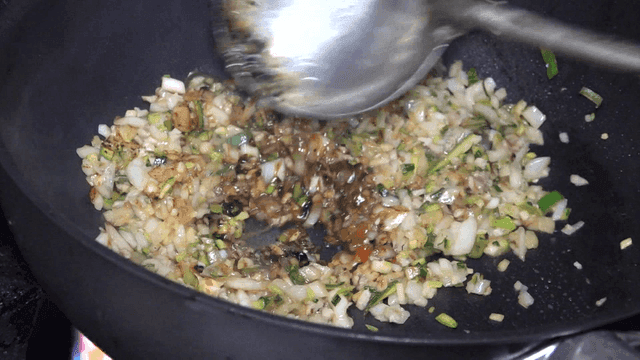 Ladle stir-frying chunjang and vegetables in a hot wok
