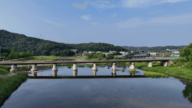 A bridge over a calm river with hills