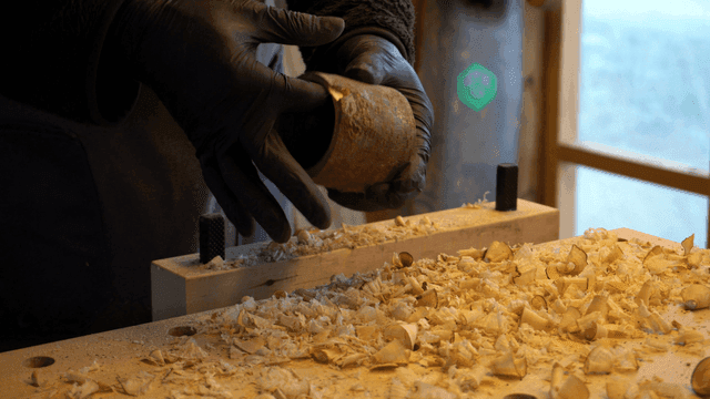 Woodcraft artisan inspecting a large hole in a wooden piece on workbench