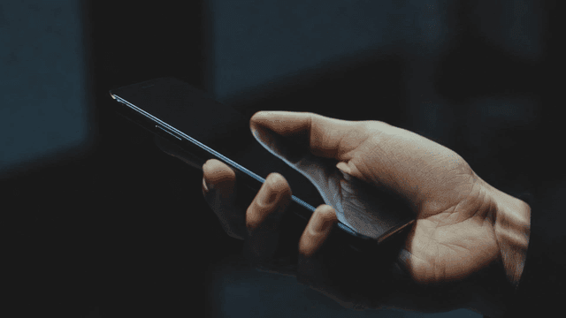 어두운 방에서 스마트폰을 들고 있는 손