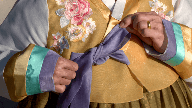 Elderly person tying a hanbok ribbon