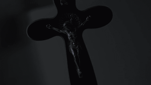 어두운 조명 속 예수가 있는 나무 십자가