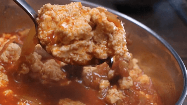 Spoonful of spicy seafood soup with soft bean curd