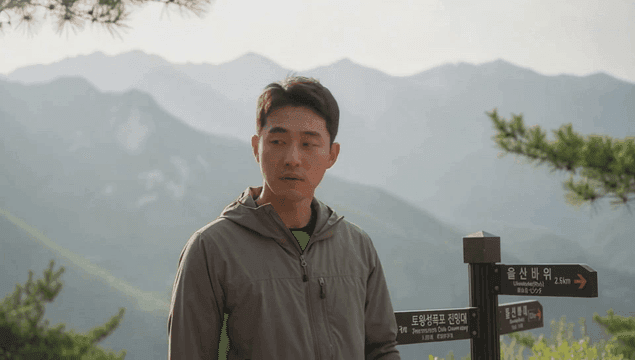 산길 표지판 앞에 서 고민하는 남자