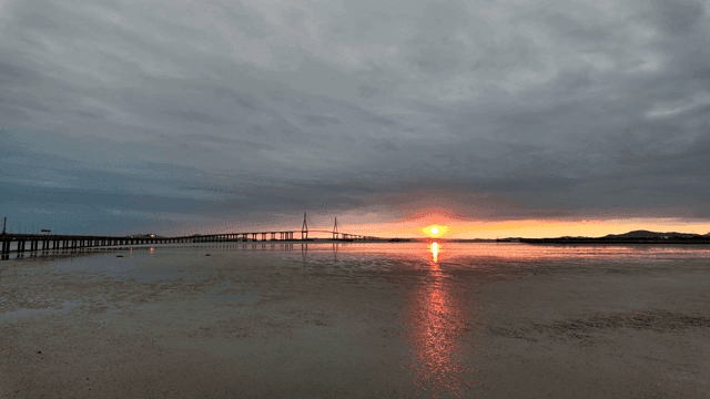 Bridge over calm sea at sunset